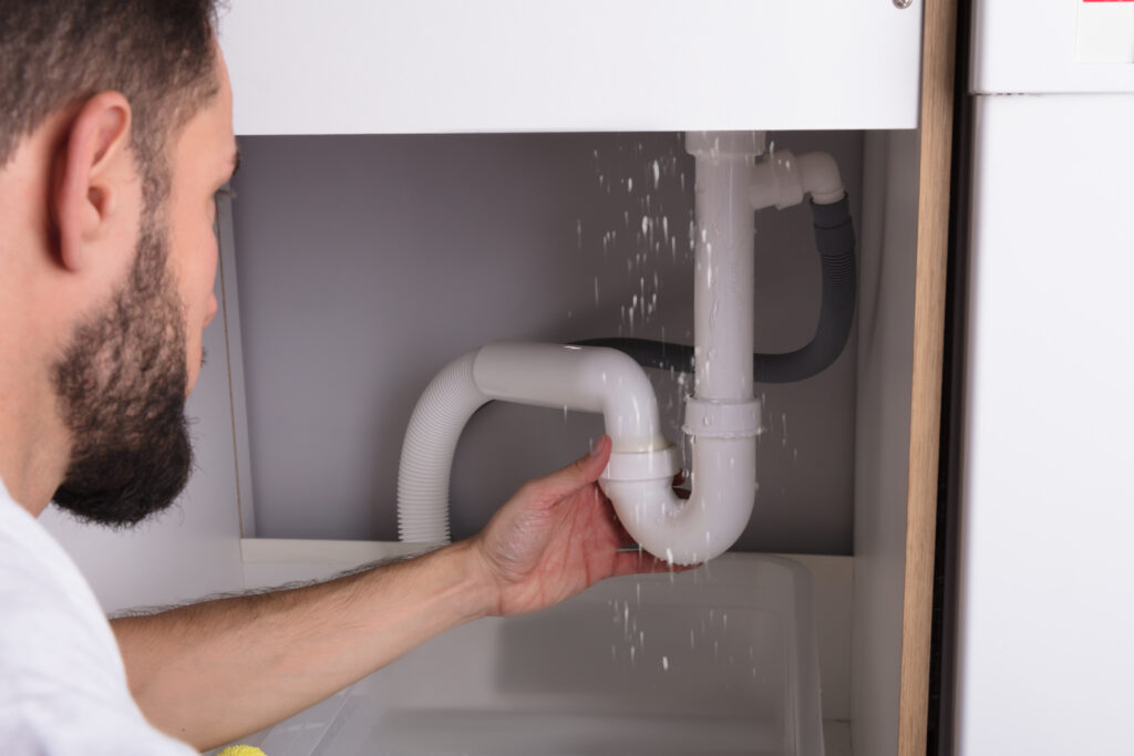 Plumber inspecting leak under sink