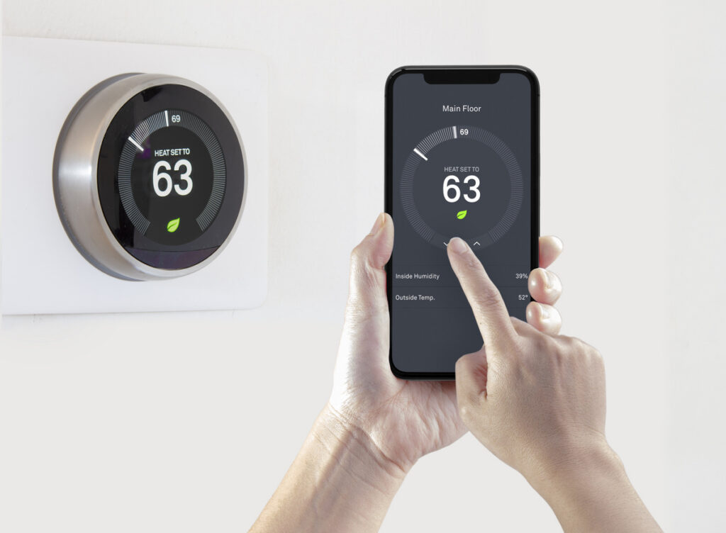 A person using a smart phone application saving energy with a wireless smart thermostat